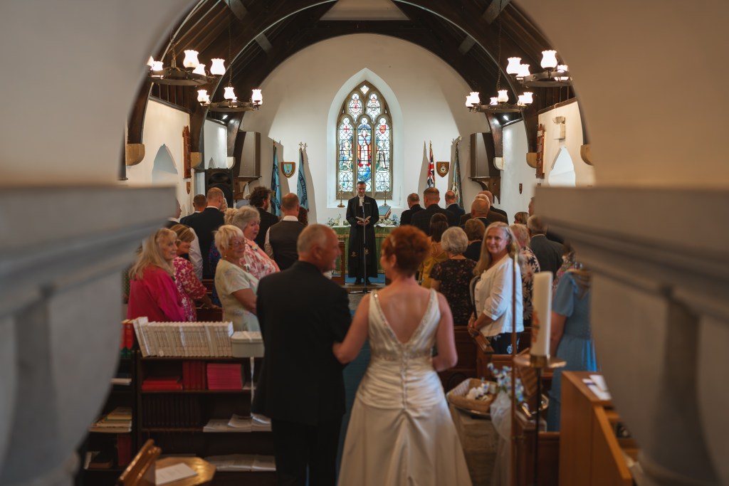 Bride being walked down the aisle in a church wedding ceremony.